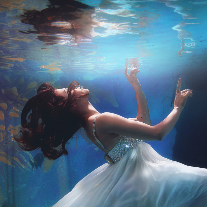 Author image of a woman floating underwater in a flowy white dress